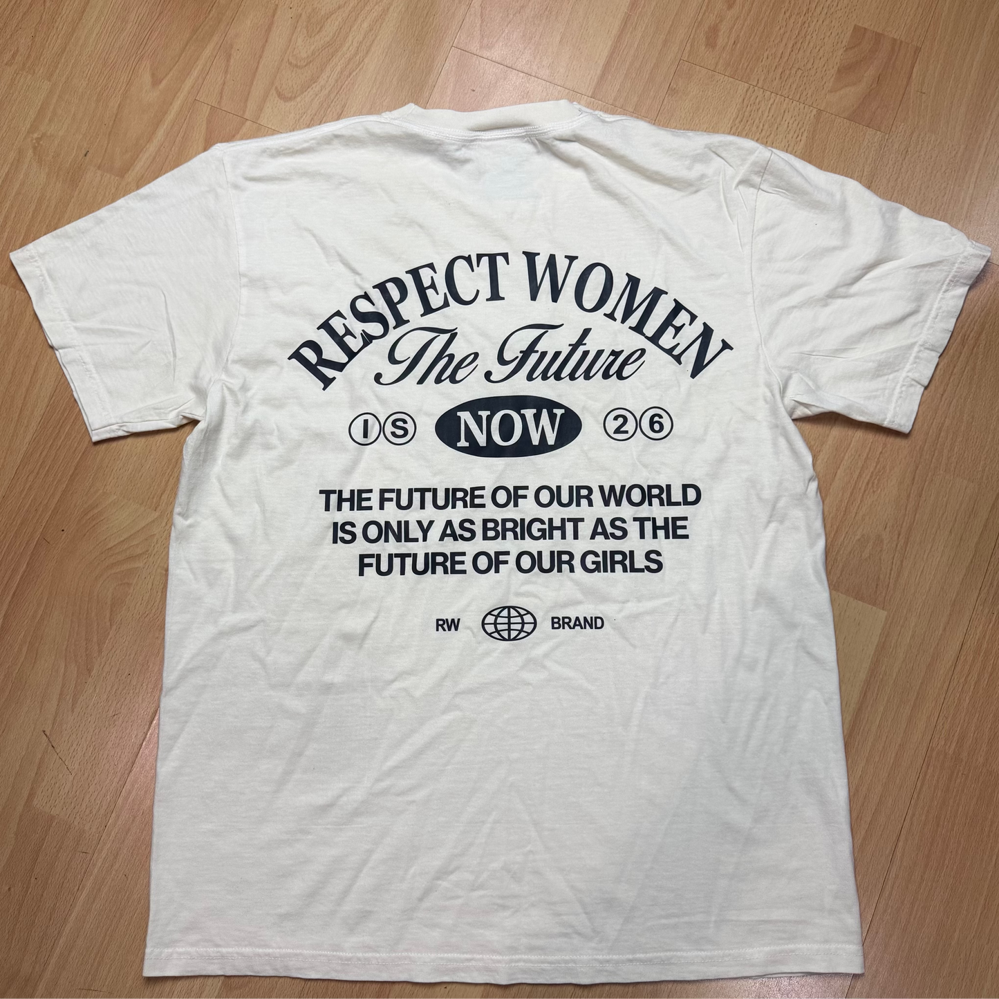 Cream t-shirt with black text on a wooden floor