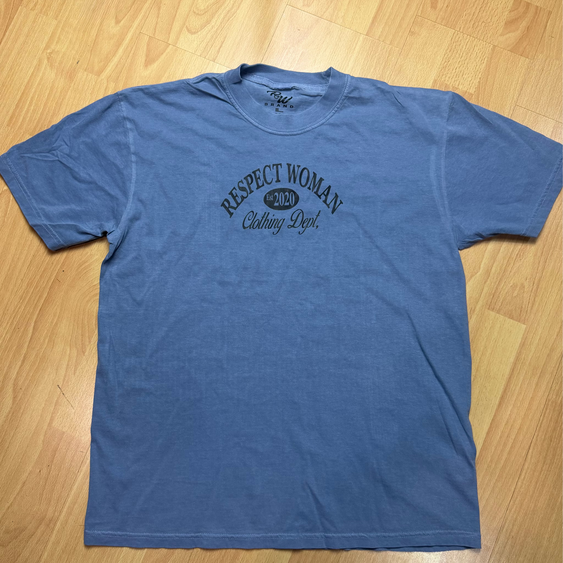 Denim colored t-shirt with Black RW Clothing Dept logo on a wooden floor
