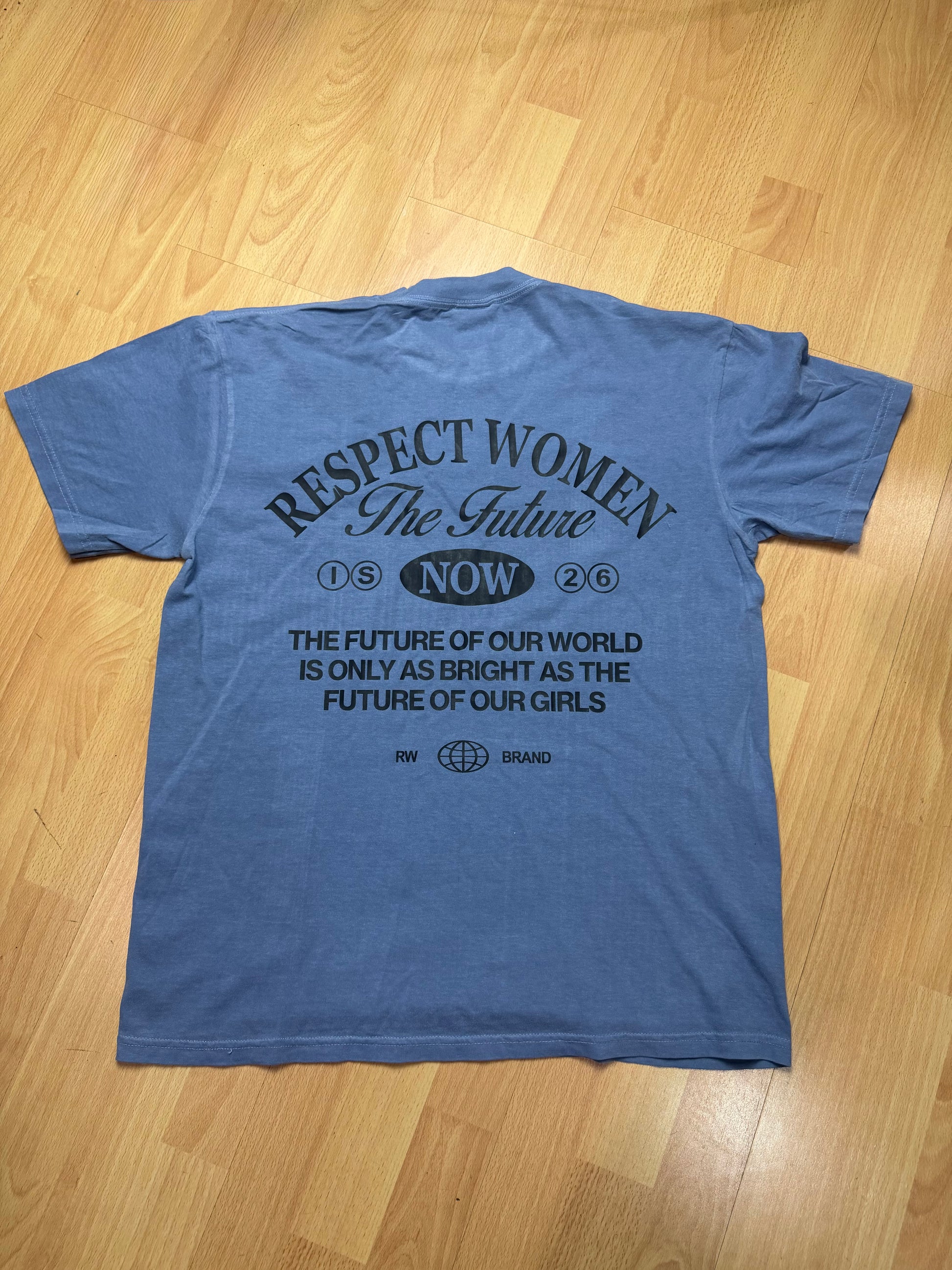 Denim colored t-shirt with Black RW Clothing Dept logo on a wooden floor